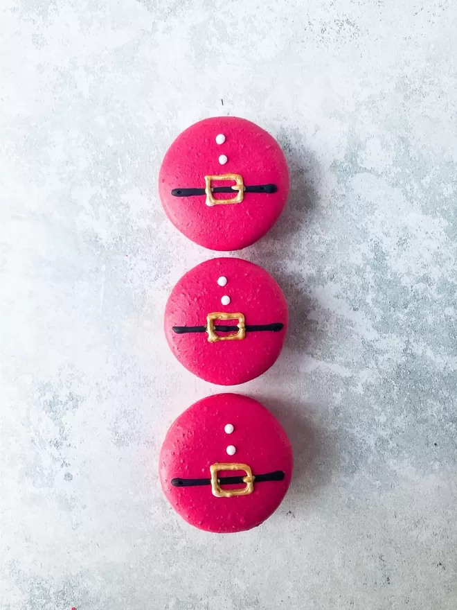 three red macarons decorated to look like santa sitting on top of each other