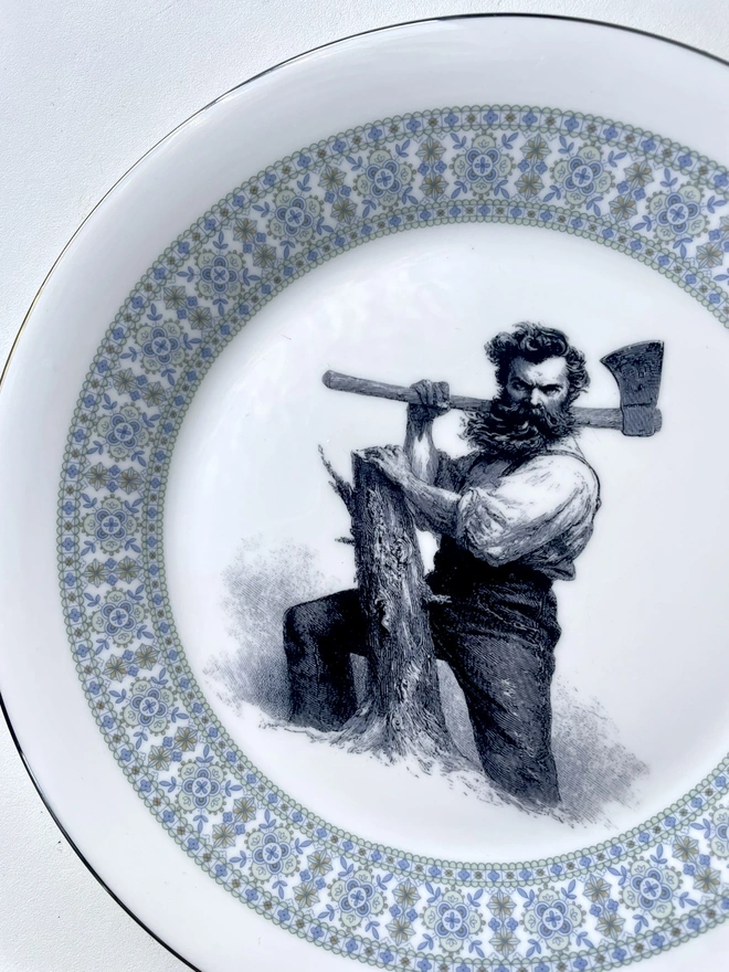 vintage plate hanging on a white wall, it has a decorative border, with a printed vintage illustration of a wild beard lumberjack in the middle 