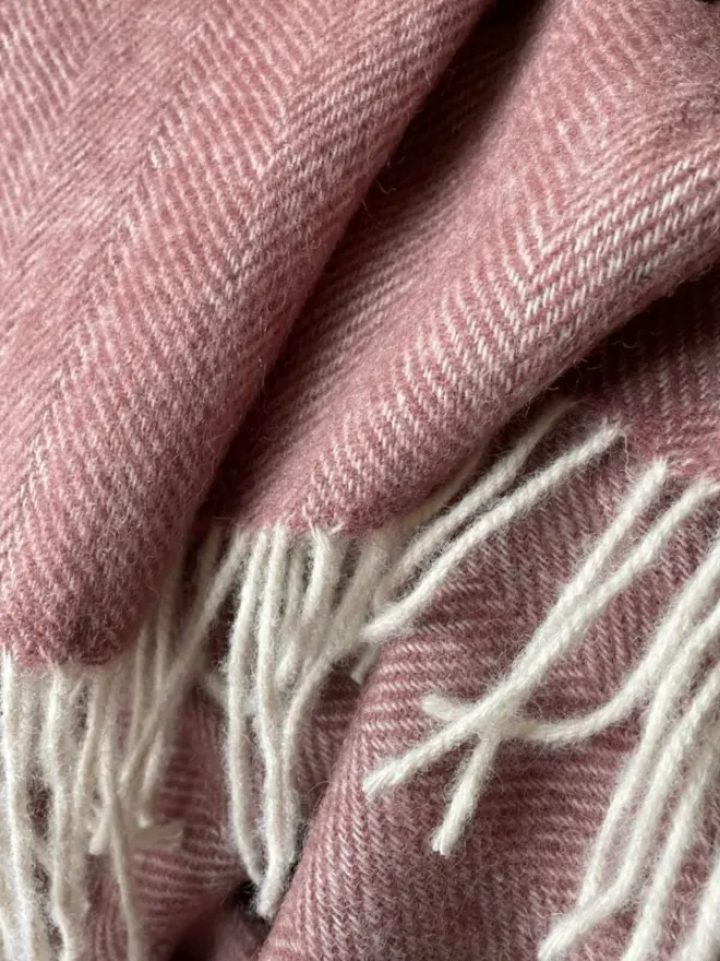 Lambswool dusty pink throw with white tassels.