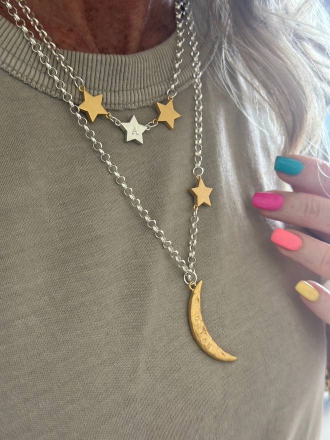 model wears a trio of linked star charms in mixed metal on a silver belcher chain