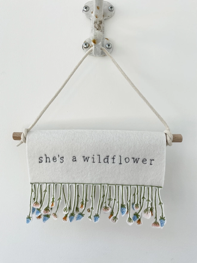 shes a wildflower banner on a hook on a wall