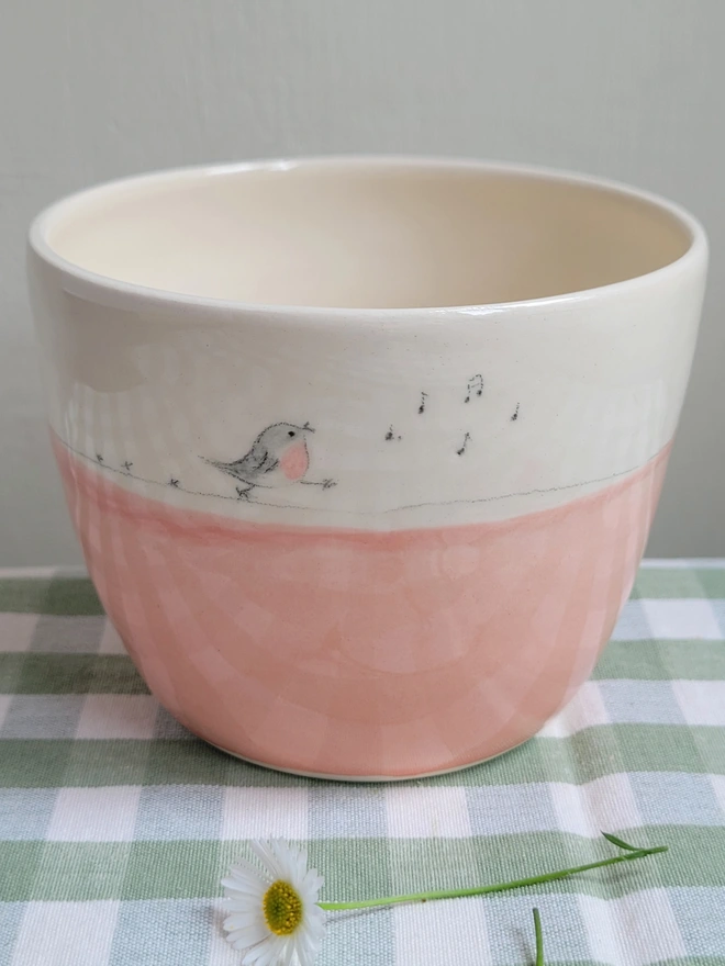 pink ceramic pottery tumbler with pink robin bird  on a green gingham tablecloth