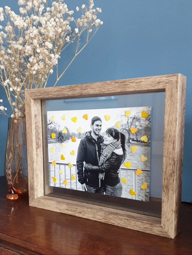 B&W couple photo, with hand embroidered shades of yellow hearts in double glass frame on desk