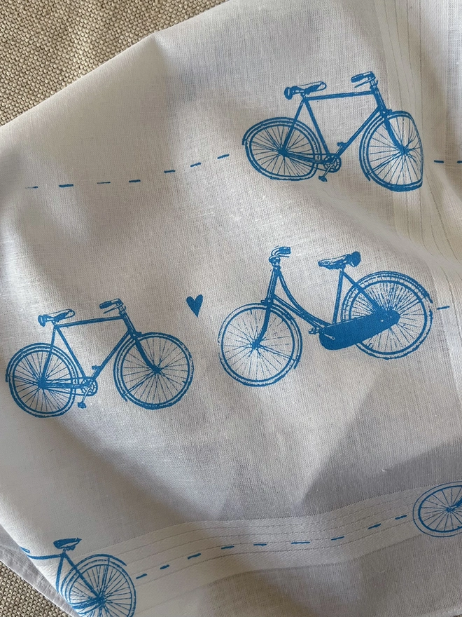 Detail of a Mr.PS white cotton handkerchief printed with a pattern of vintage bicycles with little hearts in sky blue