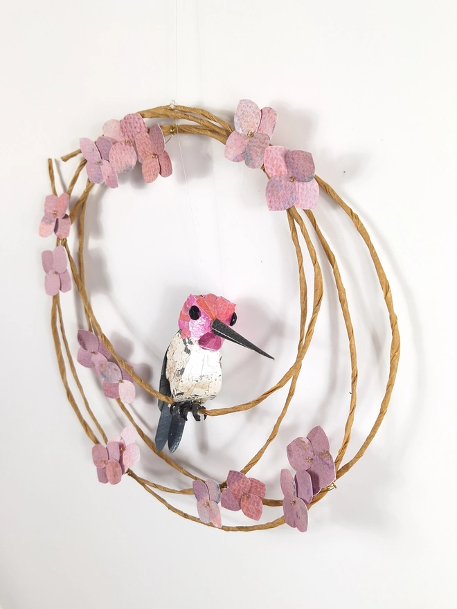 side view of a paper sculpture wall hanging, depicting a pink hummingbird