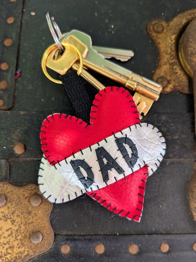 A red leatherette heart keyring, with black lettering spelling Dad across a white scroll