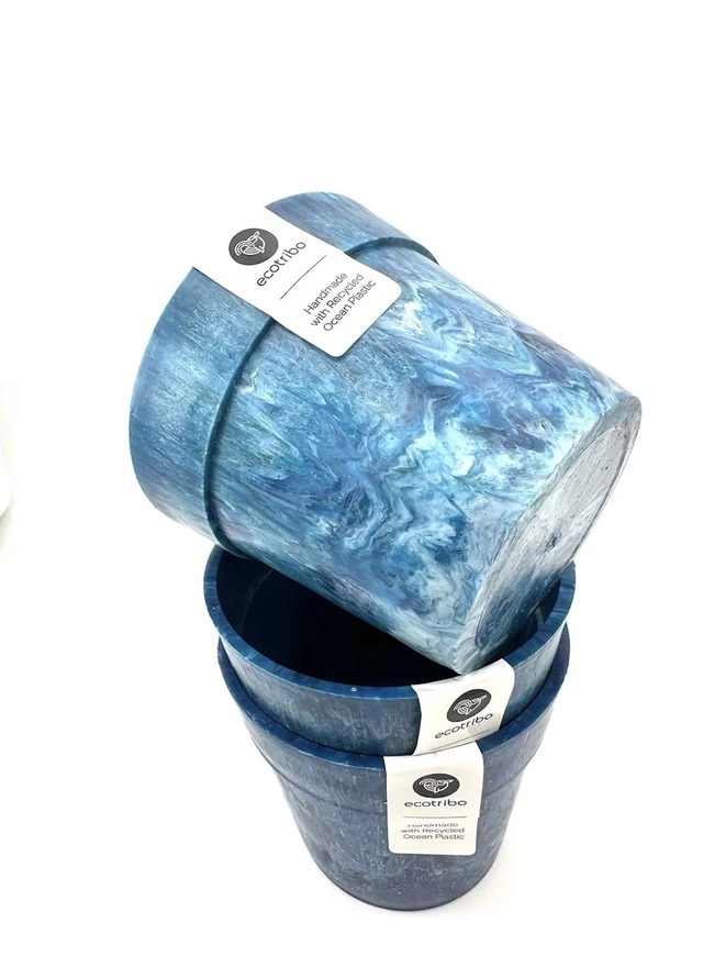 Small Blue Ocean Plastic Plant Pot , a collection of blue recycled pots sitting on a white surface against a plain backdrop. 