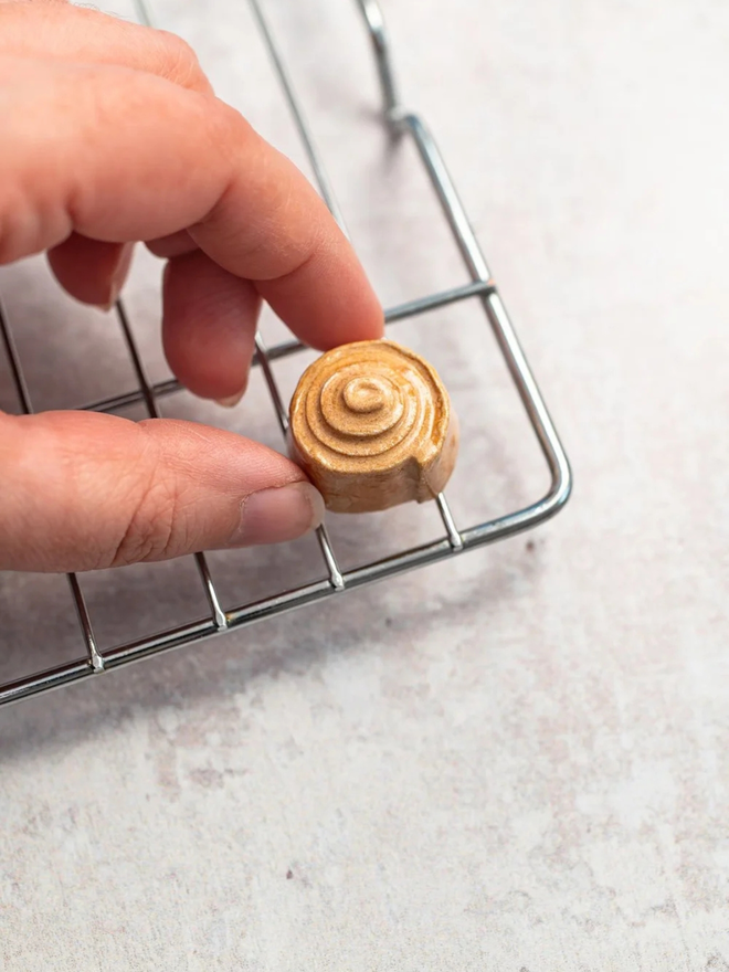 ceramic pastry magnets. a ceramic cinnamon bun magnet on a baking tray.
