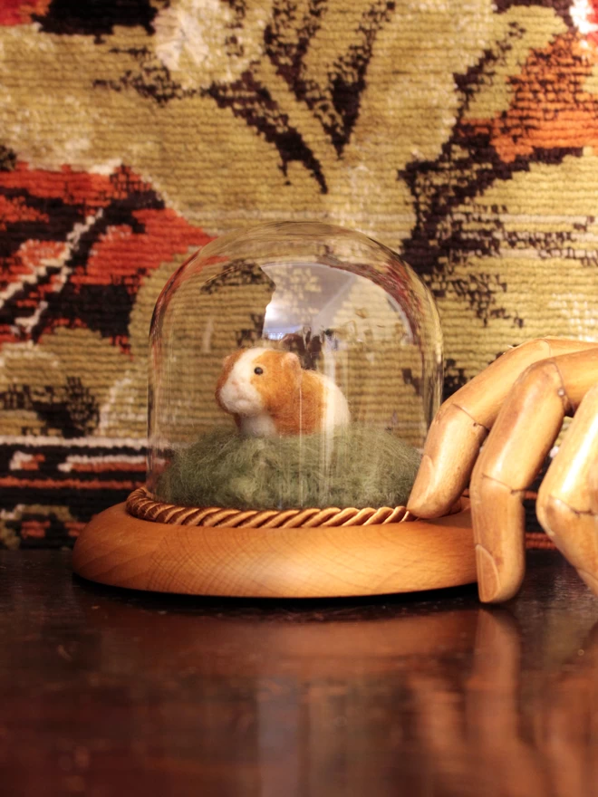 Needle-felted guinea pig sculpture in glass dome