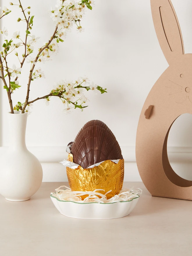 salted caramel milk chocolate easter egg. a chocolate egg photographed partially unwrapped from gold foil