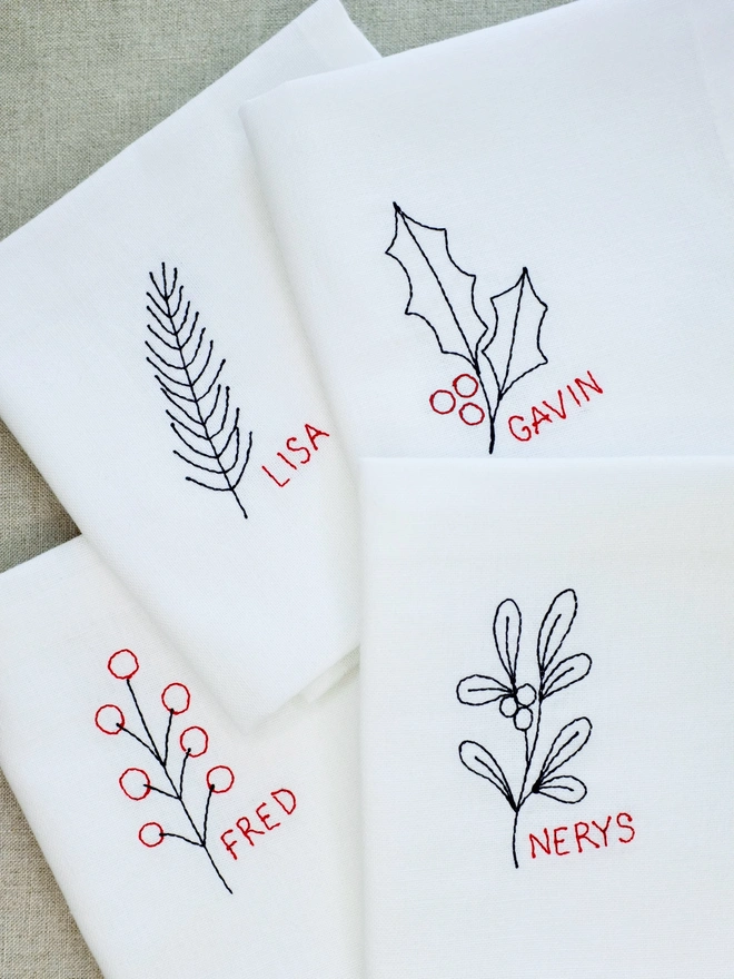 Set of four botanical Christmas personalised name embroidered napkins with berry, fir, mistletoe, and holly
