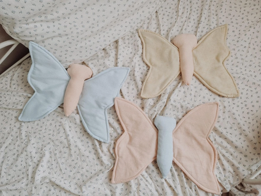 Butterfly Nursery Decoration, a group of colourful butterfly hanging decorations sitting on a child's bed. 