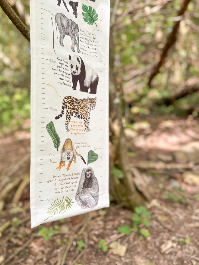 close up of the bottom of the fabric height chart featuring a baby elephant, a giant panda, a jaguar, a spider monkey and a sloth