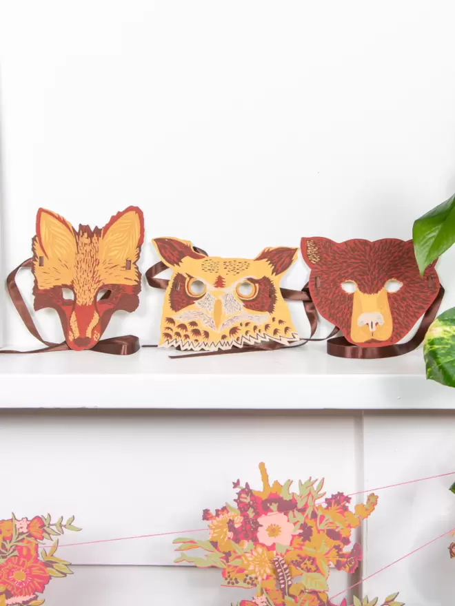 Full shot of image of all 3 animal masks displayed on shelf