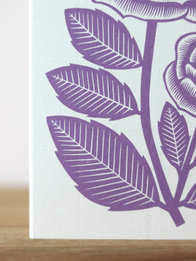 A greetings card featuring a purple rose flower based on an original linocut print