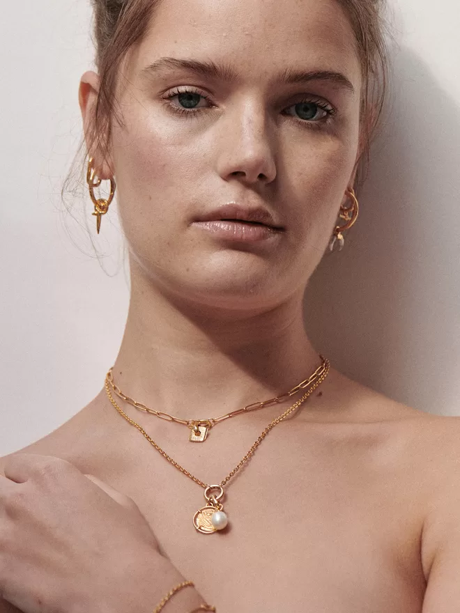 Woman wearing gold necklaces with charms and pendants