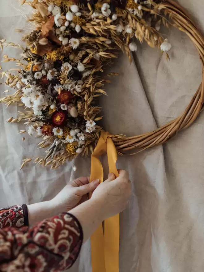 Autumn Colours Wreath seen against a white wall with an Yellowribbon