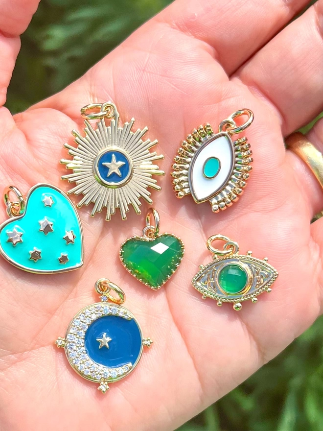 Collection of turquoise, blue and green talisman charms in the palm of a hand