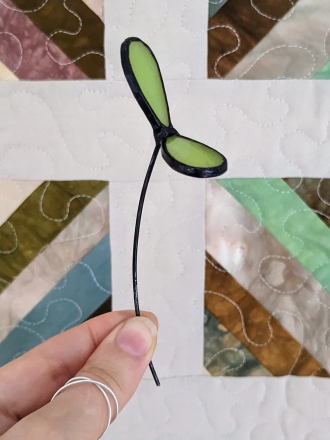 Hand holding stained glass seedling