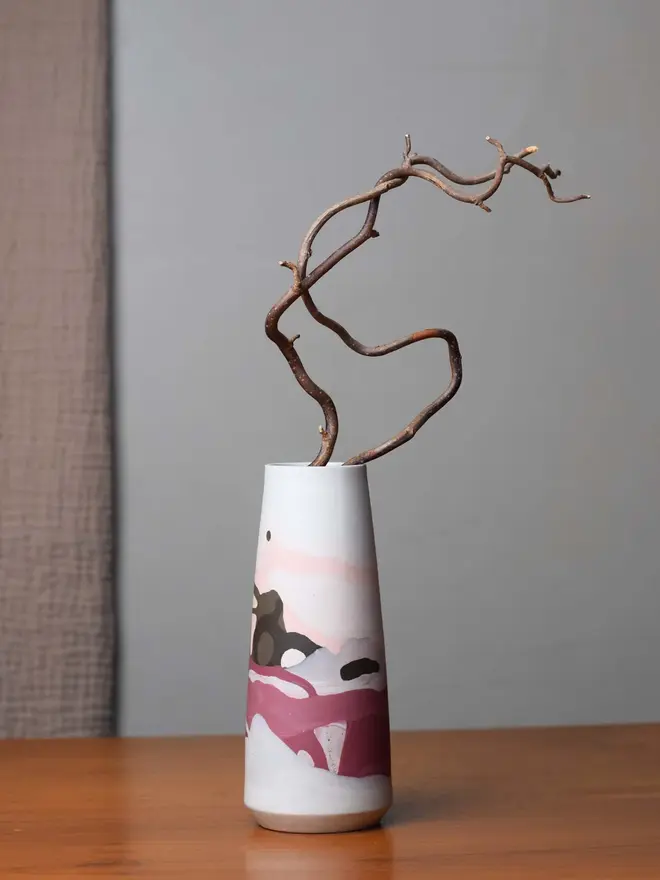vase on wooden table, vase has streaky pattern in shades of purple, brown, and pale pink