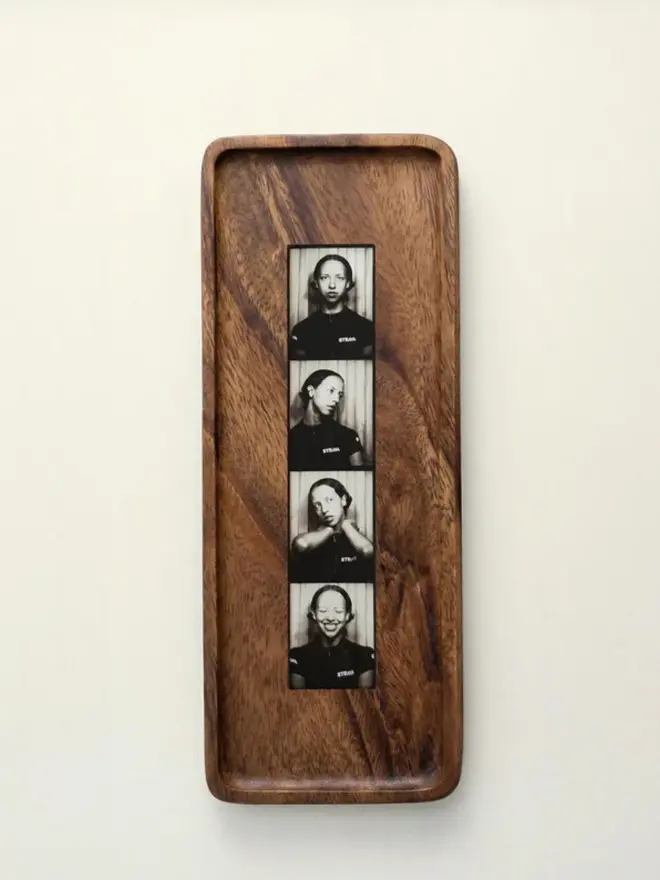 Walnut Photobooth Frame For Photo Strip Prints, hanging on a white wall. 