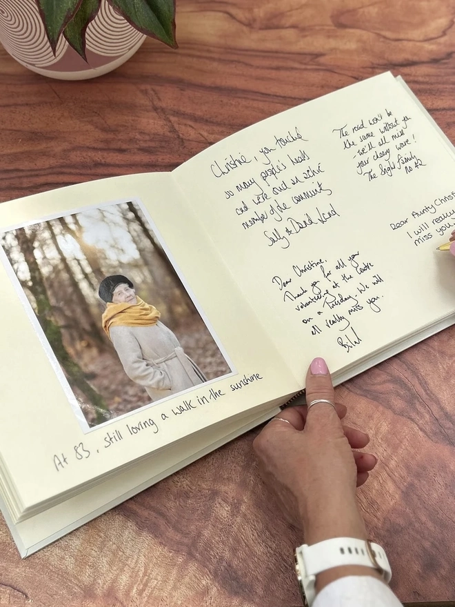 Large Personalised Condolence Book Bound And Embossed, book opened on wooden surface. 