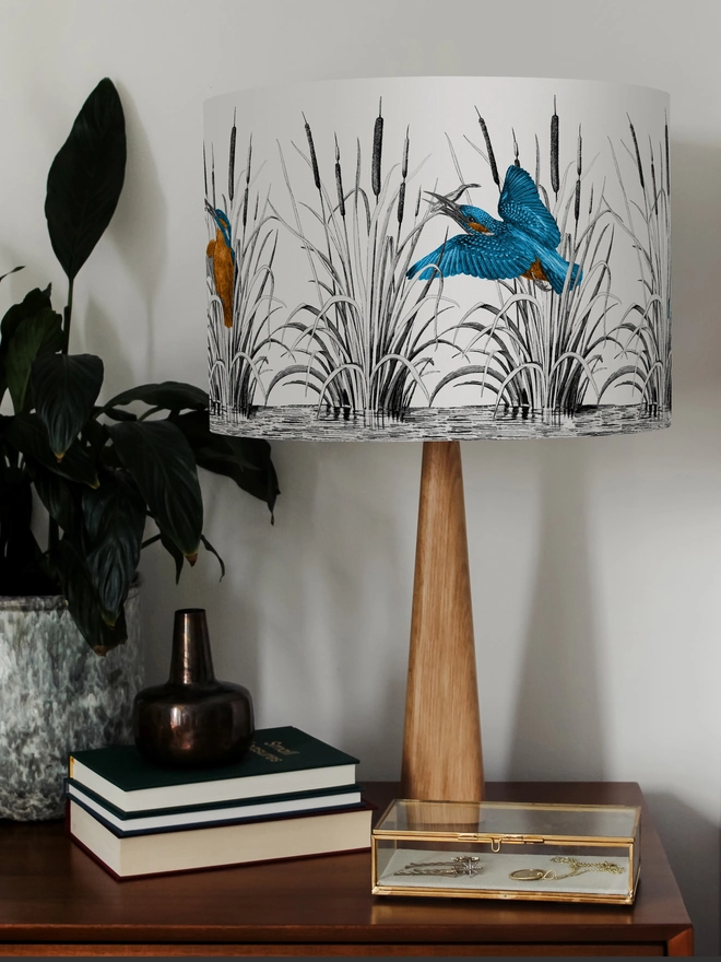 Handmade lampshade featuring vibrant kingfishers among bulrushes in a whimsical countryside-inspired design, combining nature, colour, and artisan style.