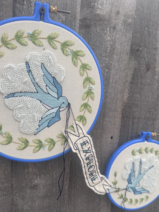 Two blue wm roisery hoops two blue birds banner with the word explore it 