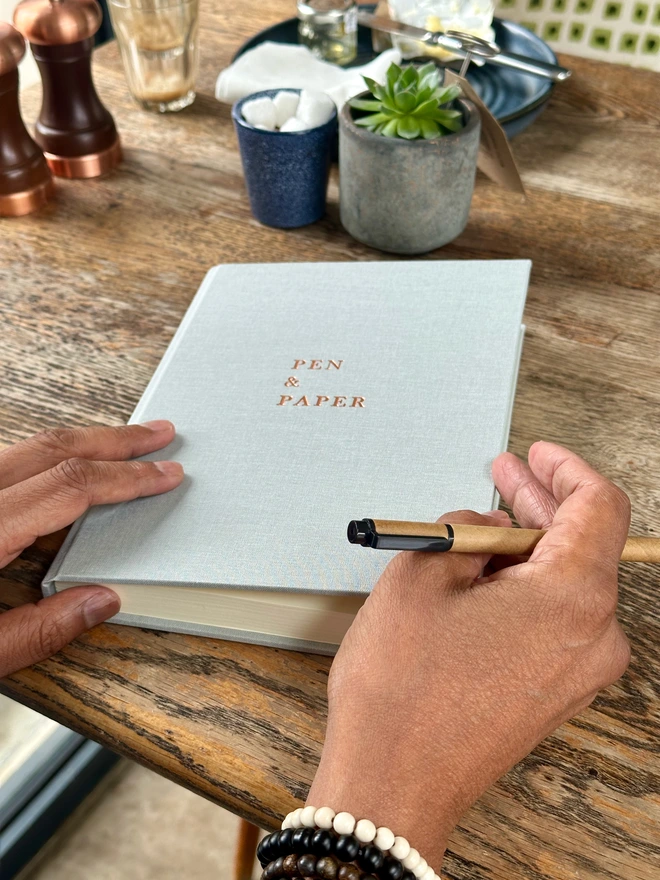 a person is about to start writing in their journal which is placed on a coffee table. In the background you can see the rest of their brunch.