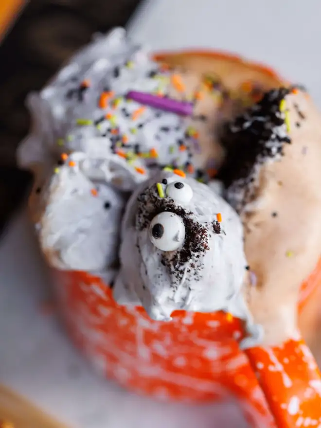 The Mallow Makers close up of monster marshmallow fluff on hot chocolate in orange mug with sugar sprinkles and eyeballs