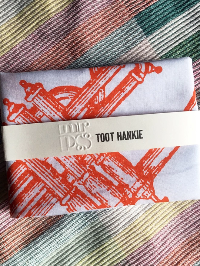a folded Mr.PS toot hankie on a stripy cloth