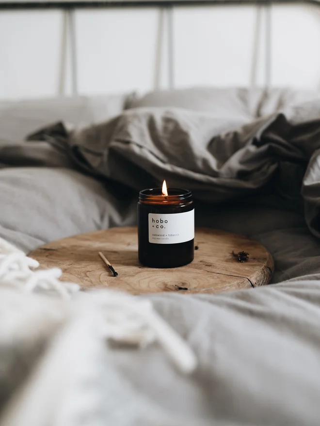 oakwood and tobacco medium jar candle in cosy bedroom 