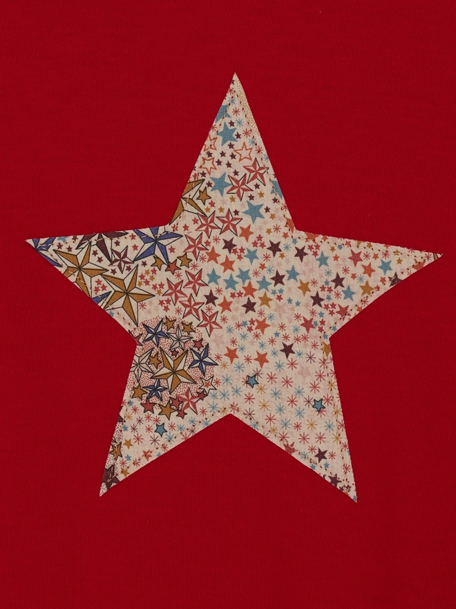a red tee with a christmas star cut from starry liberty print sewn onto the front, close up of the appliqué sewing