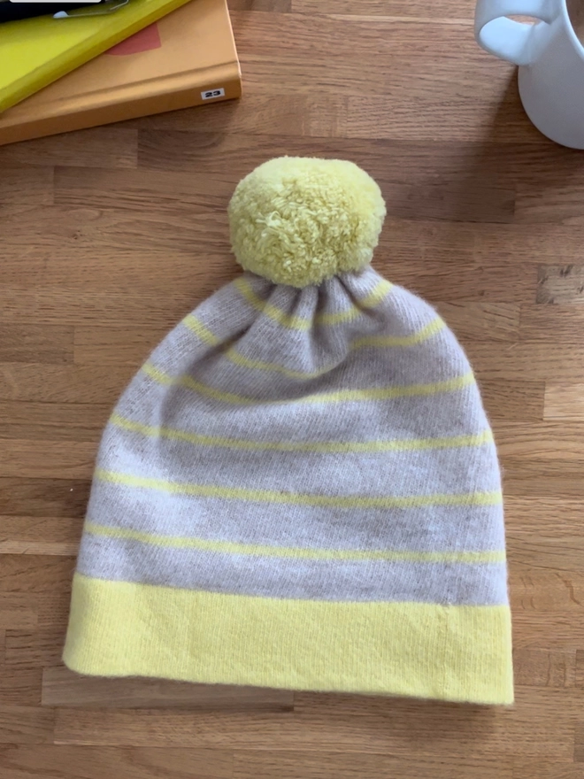 Yellow Oatmeal striped beanie hat laid flat on table