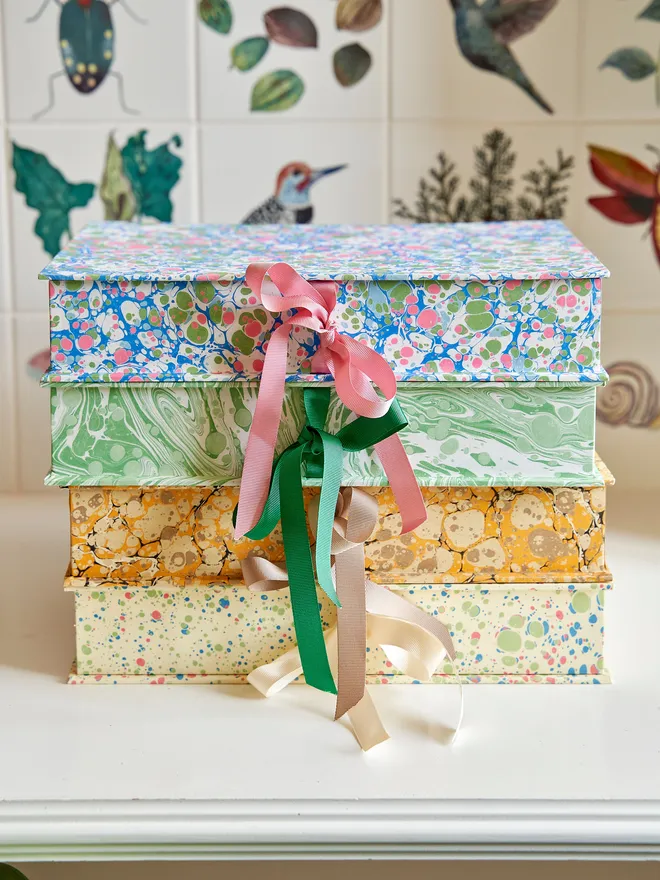 stack of 4 A5 keepsake boxes. each features a unique marbled pattern and a ribbon-tie closure