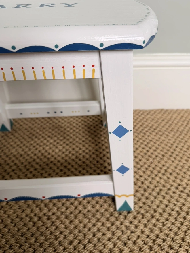 Side view of Childs christening step stool with blue and yellow handpainted detail. 