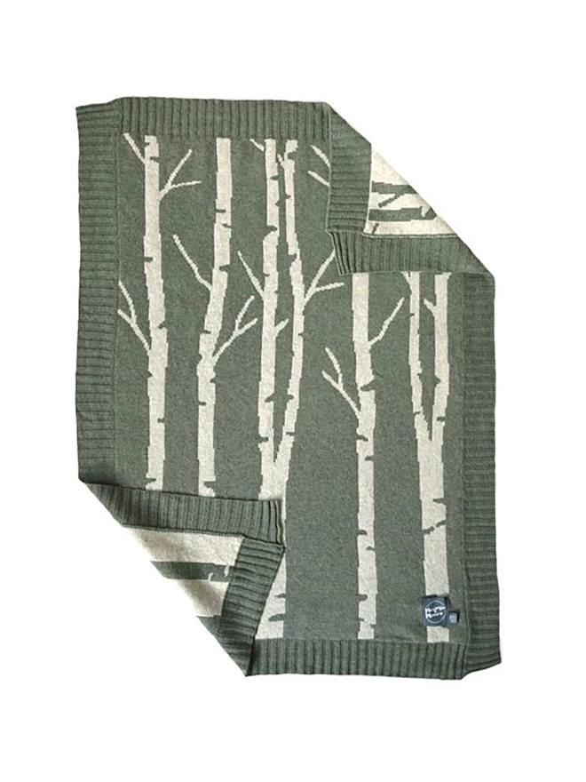 Product shot of the front of the birch forest baby blanket, moss green background with paler green silver birch tree pattern.