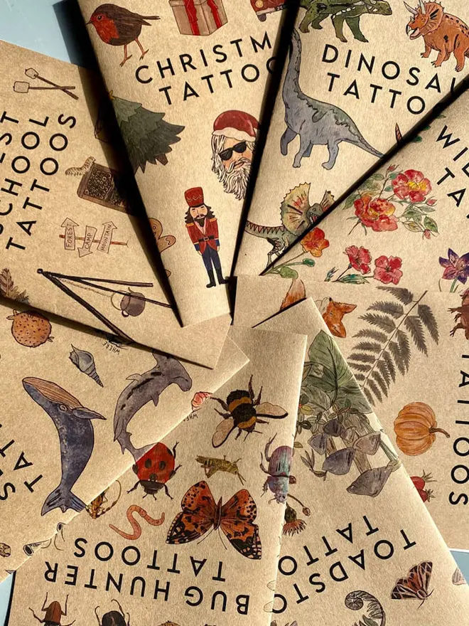 A fan arrangement of brown kraft paper tattoo booklets with various themes.