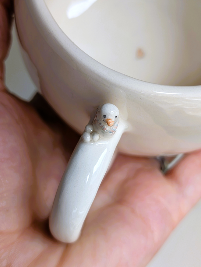 white cup with a tiny ceramic snowman and snowballs on the handle 