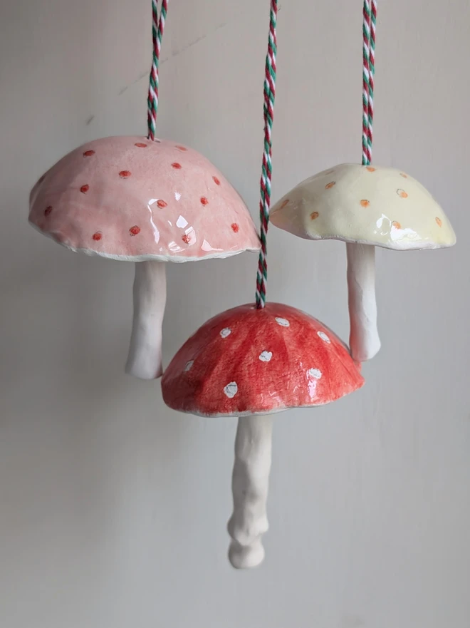 red, pink and yellow spotty ceramic mushroom hanging bells against a pale grey background