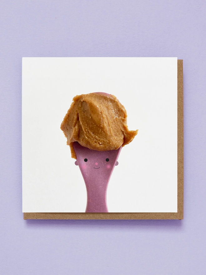 A purple spoon with a cute face & peanut butter for hair. 