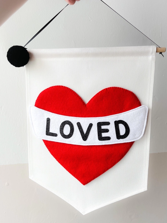 Red heart with black lettering saying loved