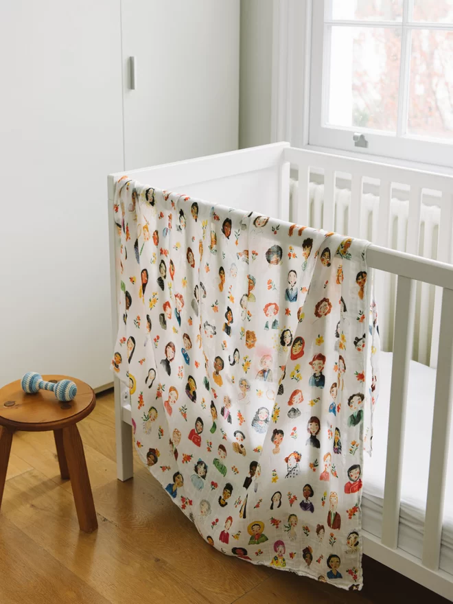 swaddle blanket of iconic women draped on nursery cot