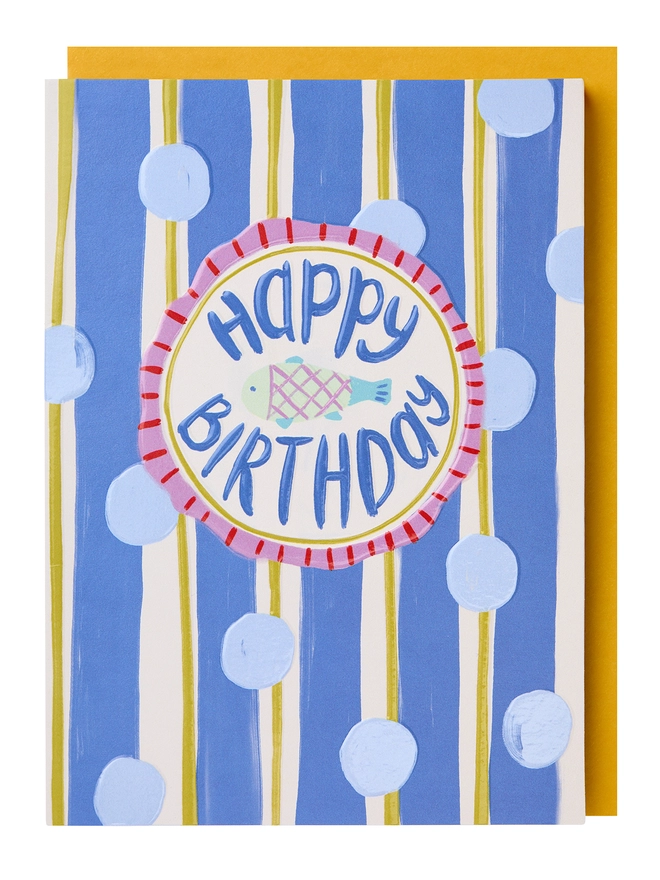 A blue white and yellow stripey card with blue polka dots and a fish illustration in the centre with the message 'Happy Birthday'
