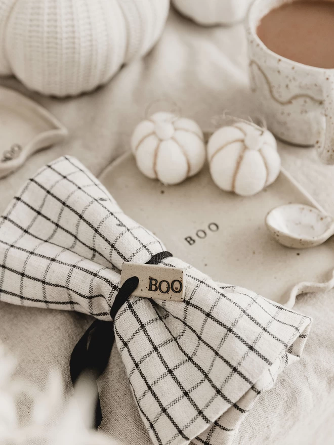 ceramic 'boo' tag tied around a white and black chequered napkin