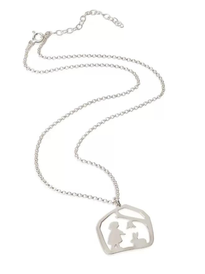 Flat lay of silver pendant on chain showing child in nature with rabbit