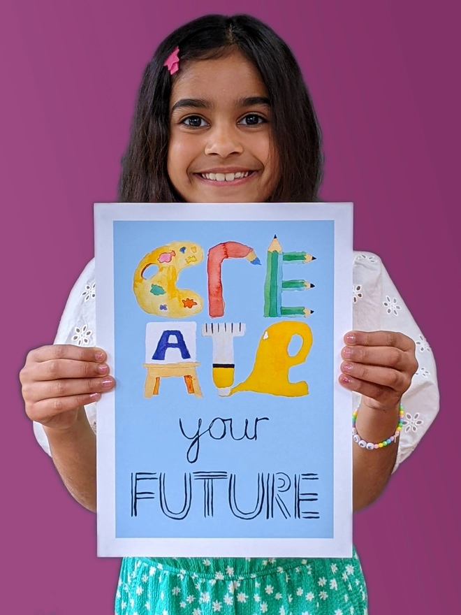 Young girl standing holding an art print saying 'Create your future'