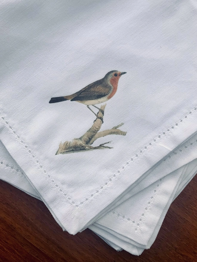 white cotton napkins with a printed bird illustration on one corner