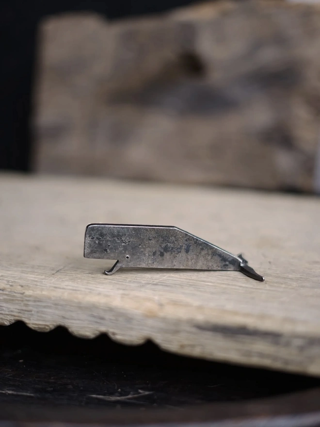 Whale Bottle Opener, a whale shaped bottle opener sitting on a wooden surface. 