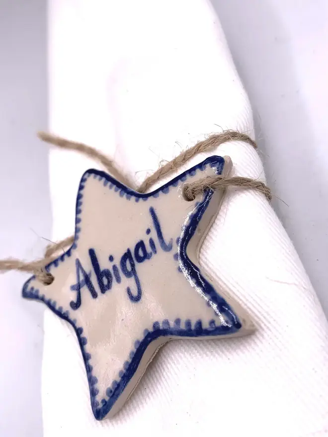 Personalised Ceramic Christmas Star Name Place Markers, a colourful star place marker sitting on a plain white surface. 